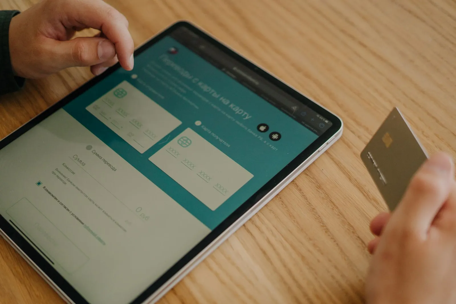 Mobile payment transfer screen on a tablet with a bank card in hand